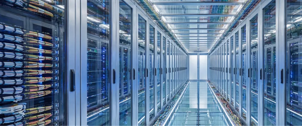 A well-lit, modern datacentre with hundreds of server racks, which needs contstant energy to process requests.