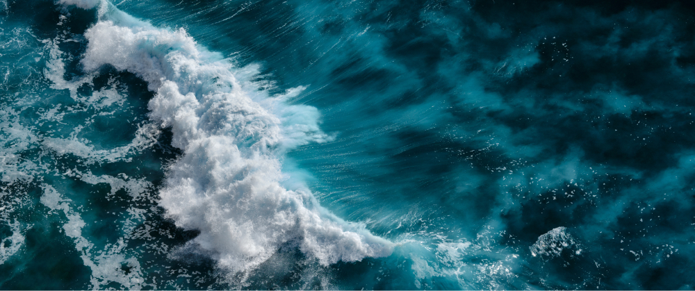 Aerial image of a turbulent sea, demonstrating the power of crashing waves in the context of harnessing wave energy.