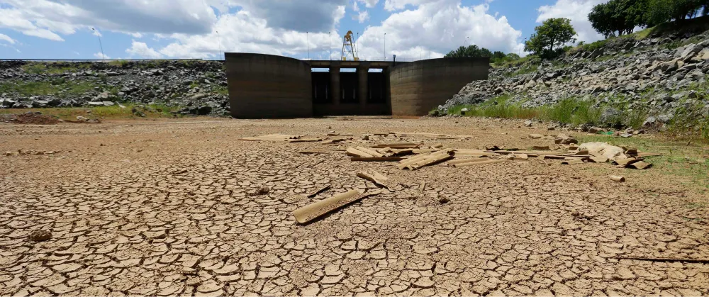 Cracked dry earth beside a depleted reservoir, illustrating the growing risk of water scarcity