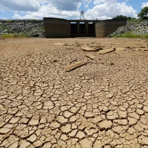 Cracked dry earth beside a depleted reservoir, illustrating the growing risk of water scarcity
